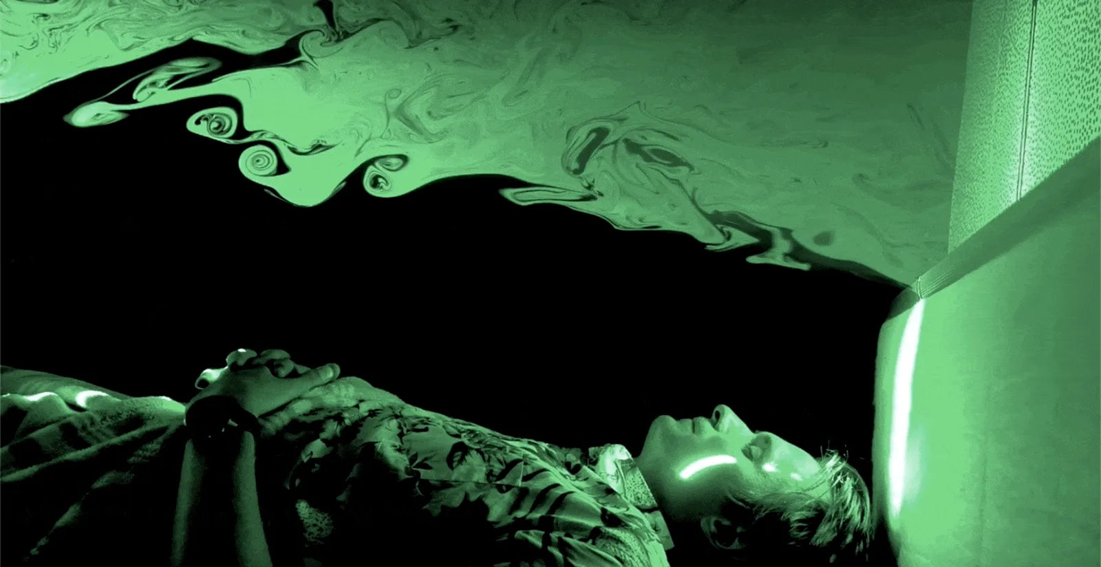 Green laser light reveals airflow above a person reclining against an AirTulip headboard